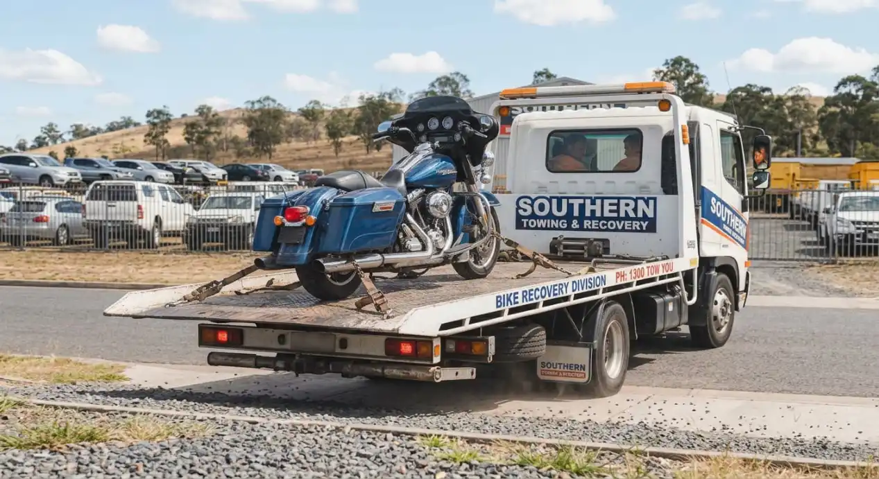 A large blue touring motorcycle securely tied down with heavy-duty straps on the flatbed of a Southern Towing & Recovery truck.