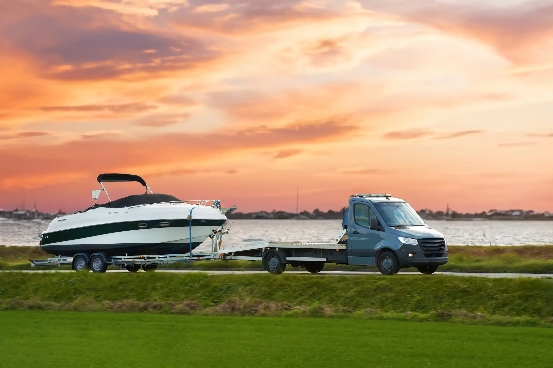 Southern Towing flatbed transporting a boat and trailer at sunset using the same low-angle loading deck we use for 24/7 caravan towing